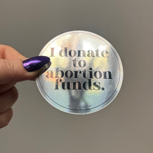 Hand holding a reflective disc with text against a plain background
