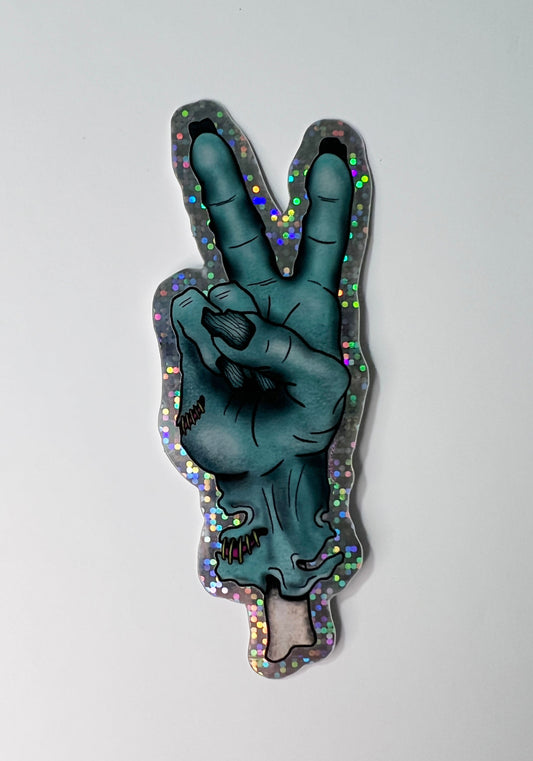 Sticker of a zombie hand making a peace sign on a light gray background