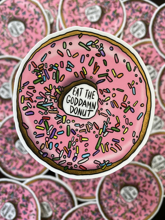 A bright pink iced donut with the text: Eat the goddamn donut 