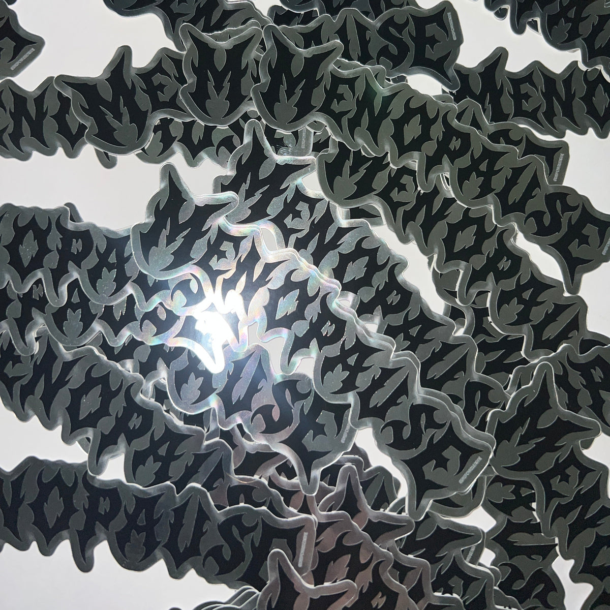 A close-up of a black and gray patterned fabric or material with a bright light reflecting through the center, showing a repeating wavy cutout design.