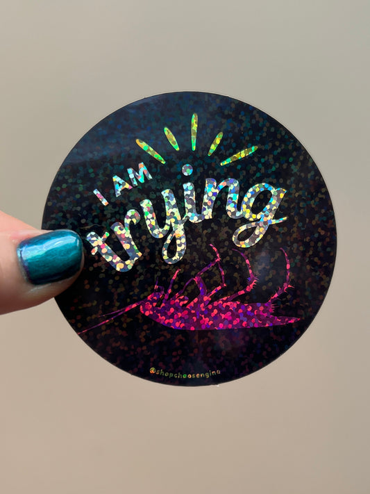 Holographic sticker with text held by a hand against a neutral background