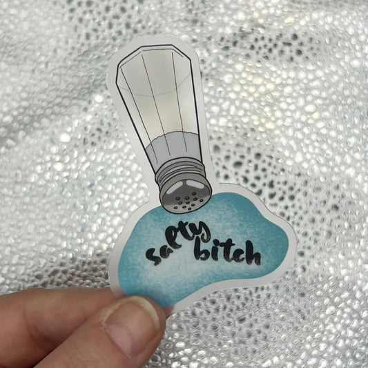 Sticker with a salt shaker design and text held over a textured silver background