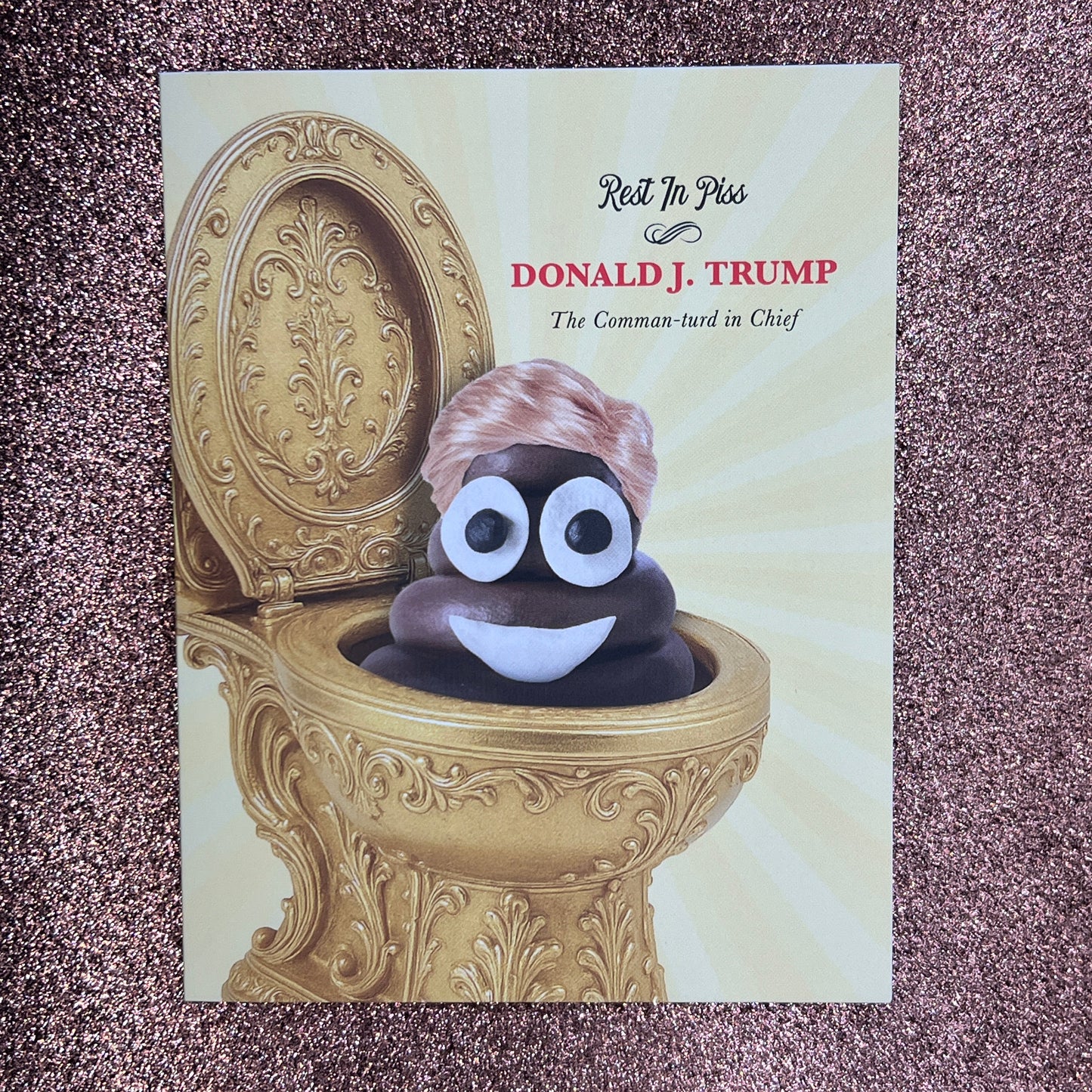 Card with a decorative gold object and a small figure on a textured surface