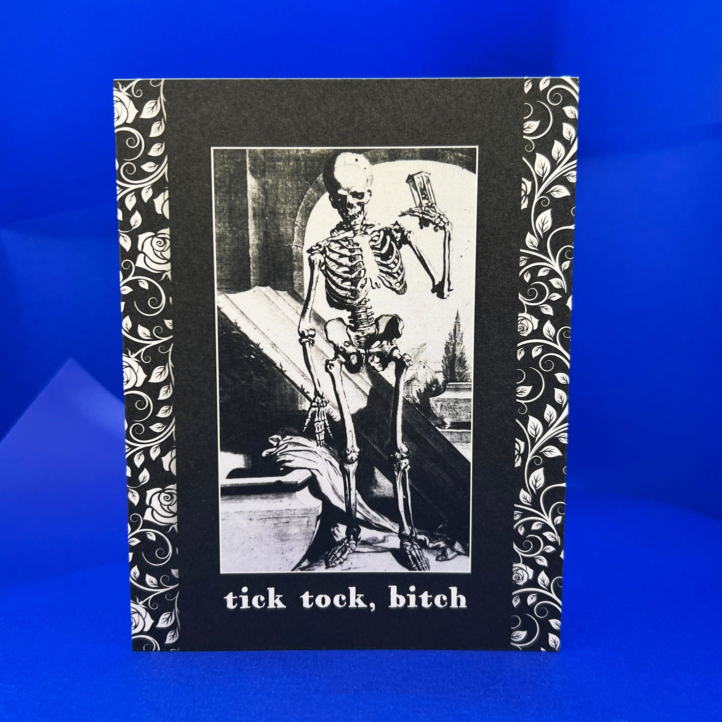 Skeletal design with text 'tick tock, bitch' on a blue background